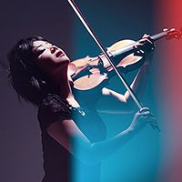 woman plays the violin in dramatic lighting